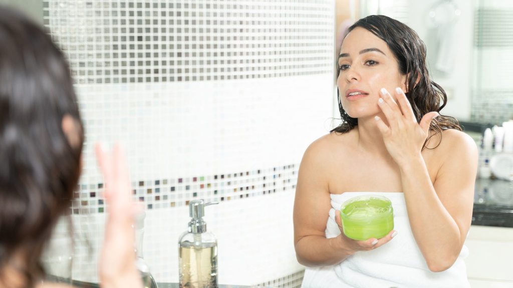 Una mujer se aplica gel de aloe vera en el rostro después de la ducha para usarlo como tónico facial.